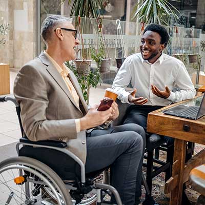 Business traveller using a wheelchair working with a colleague in an airport lounge.