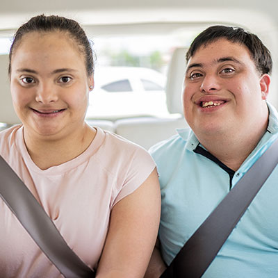 Passengers with accessibility needs travelling in the back seat of a car.