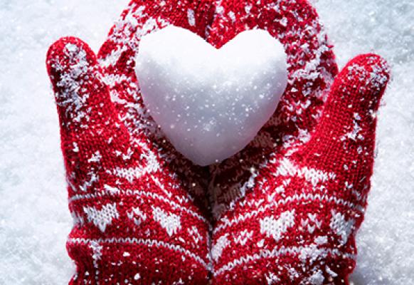 Mittens holding heart-shaped snow