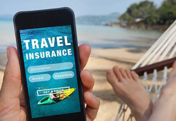 Holidaymaker reading about travel insurance on their mobile while lying in a hammock